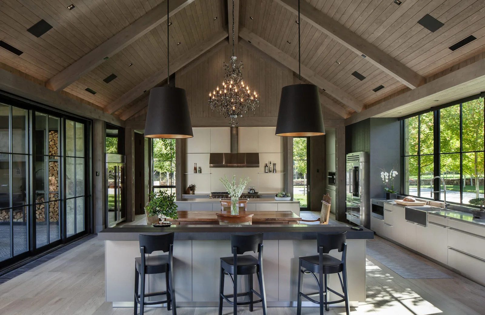 Modern luxury kitchen with vaulted wood ceiling, large island, and integrated appliances